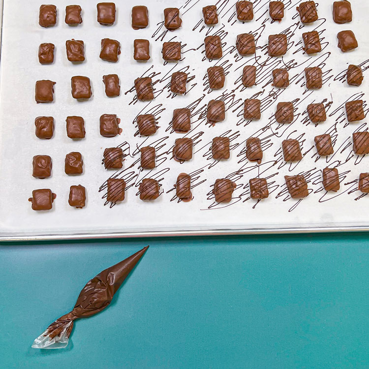 striping dipped chocolate peanut butter logs with melted dark chocolate