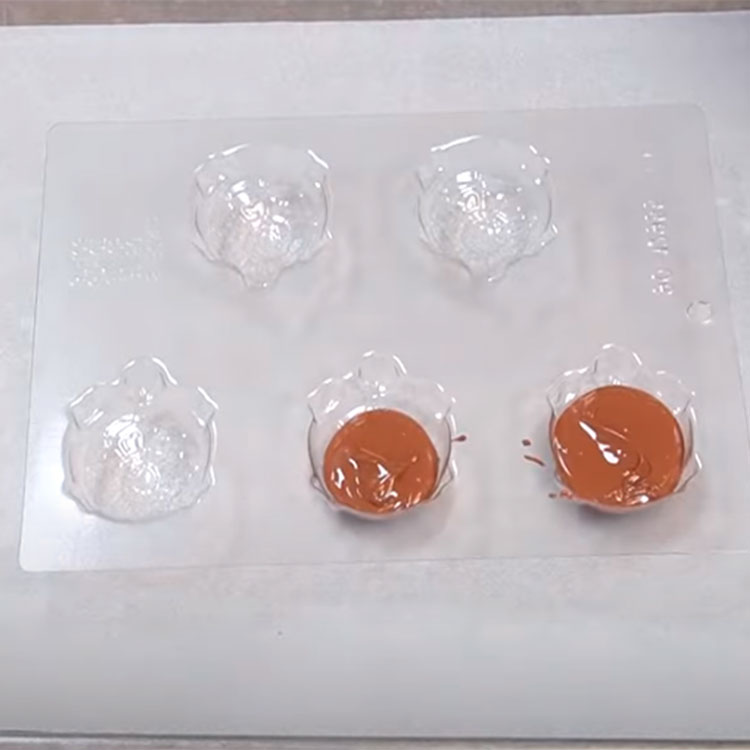 filling a turtle shaped chocolate mold with melted chocolate