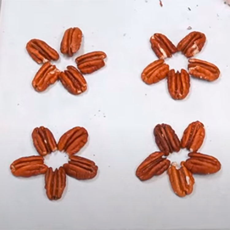 pecan halves arranged on a sheet pan to make chocolate turtles