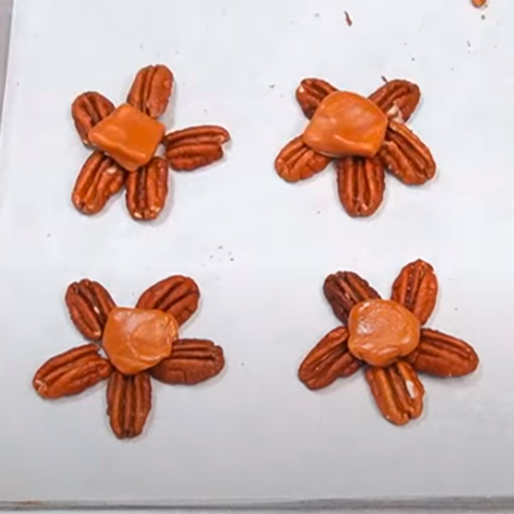 pecan halves arranged on a sheet pan to make chocolate turtles