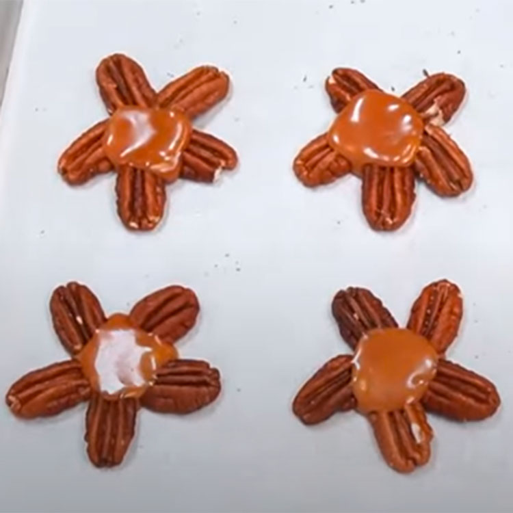 pecan halves arranged on a sheet pan to make chocolate turtles