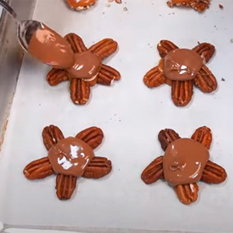 pecan halves arranged on a sheet pan to make chocolate turtles