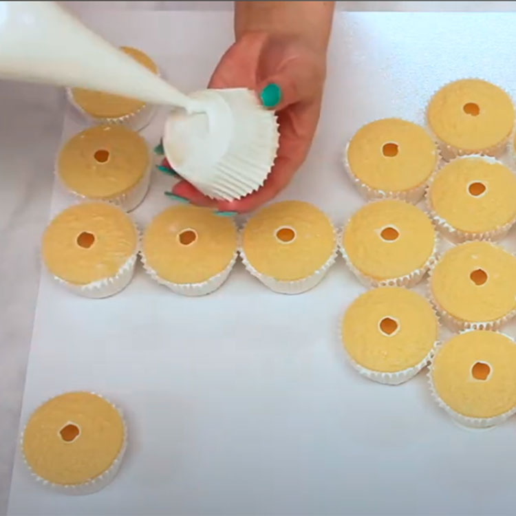 piping buttercream to bottom of cupcake to attach it to the board
