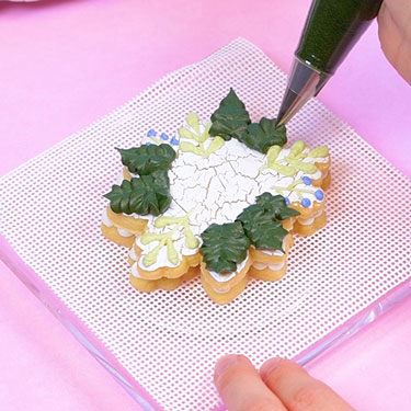 piping buttercream leaves onto cookie tart