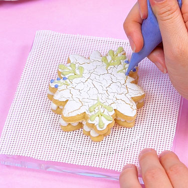 piping greenery sprigs onto sugar cookie