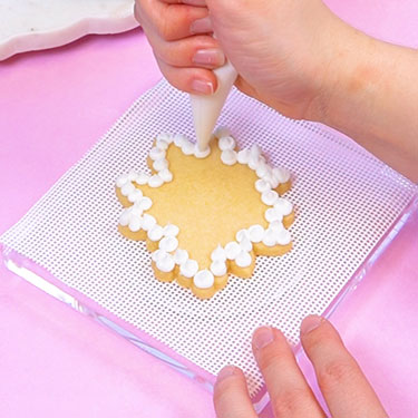 piping buttercream dollops around the edge of a cookie