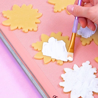 painting white food coloring onto cookie cut outs