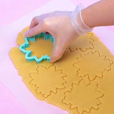 cutting out cookie dough using a floral cookie cutter