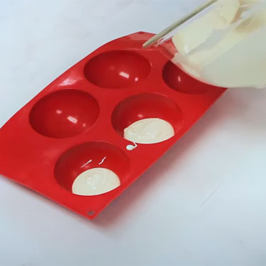 silicone hemisphere chocolate mold being filled with melted chocolate
