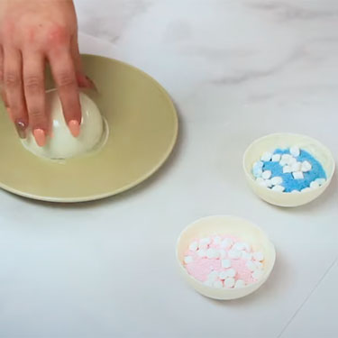 smoothing edge of hot cocoa bomb shell with a heated plate