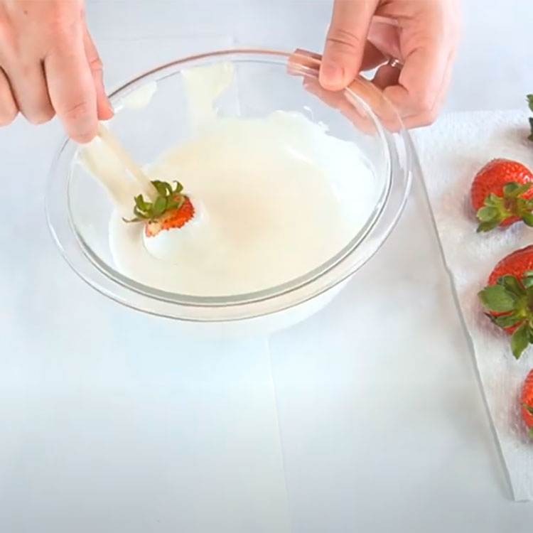 dipping a strawberry into melted chocolate