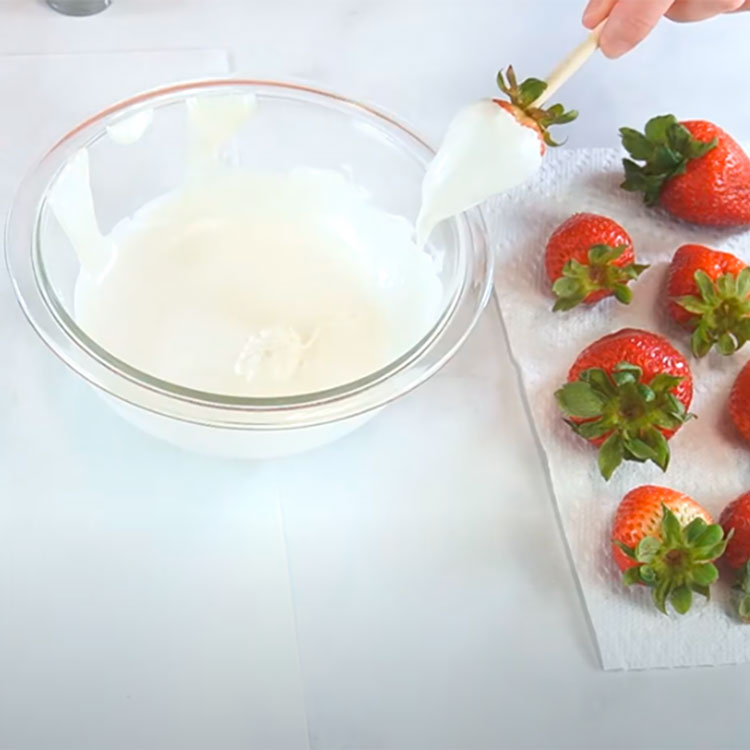 cleaning off dipped strawberry on rim of bowl