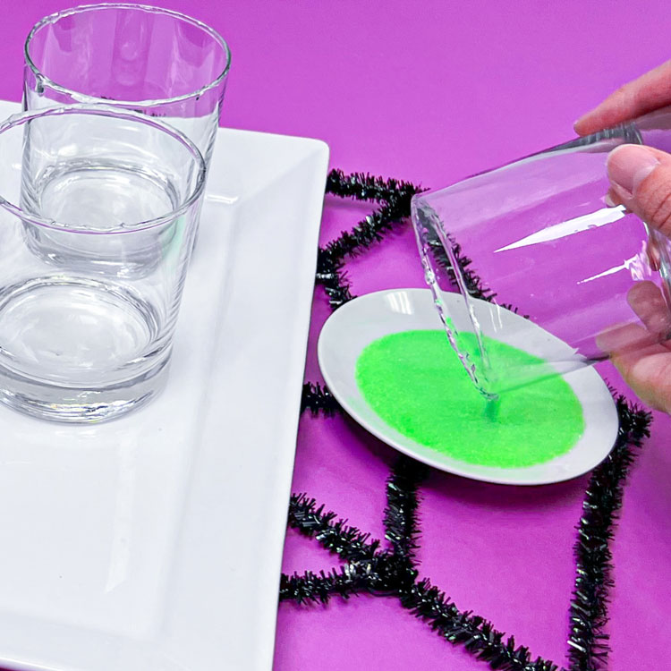 rolling glass into green sugar to make decorative rim