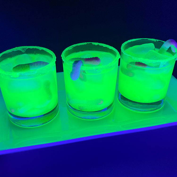 three glasses filled with glowing green drink 