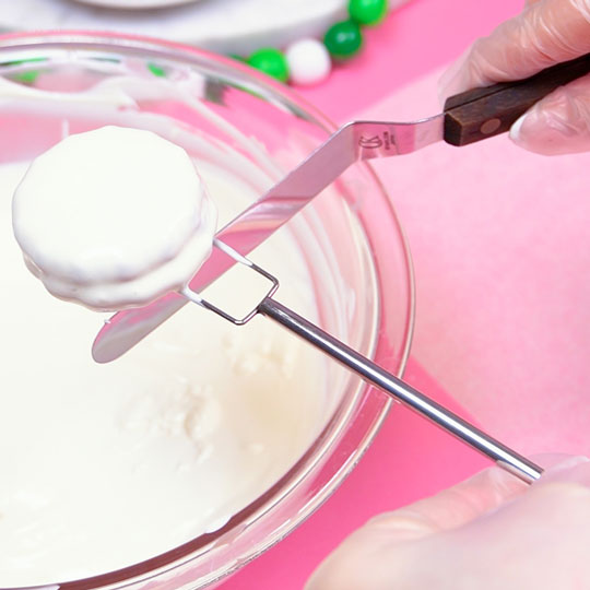 dipping sandwich cookies into melted white chocolate