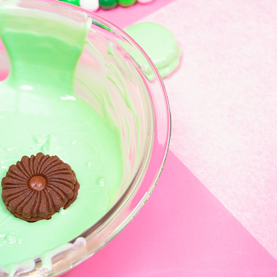 chocolate sandwich cookie in a bowl of melted green chocolate