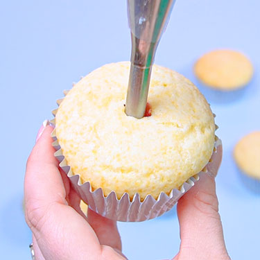 using a bismarck tip to add filling to a cupcake