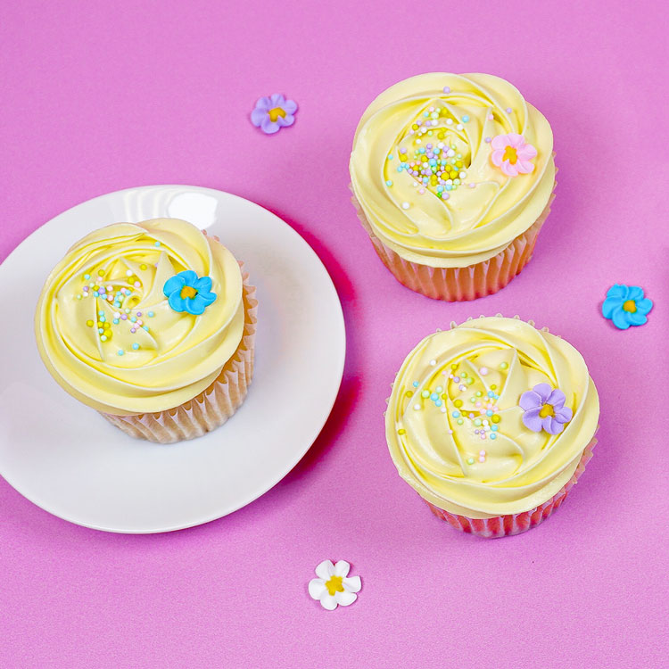 vanilla cupcakes frosted with lemon frosting and decorated with flower decorations