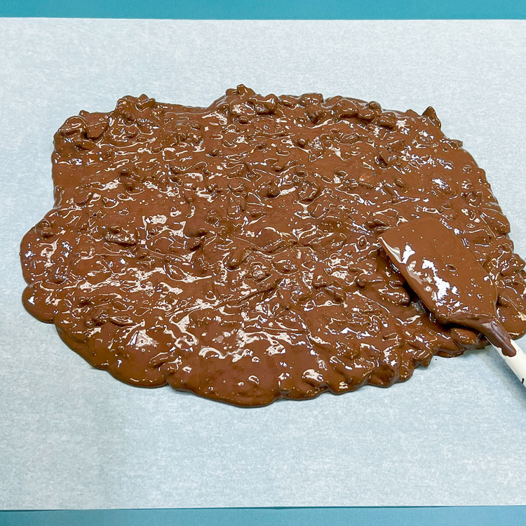 spreading melted chocolate mixed with crushed oreos on parchment