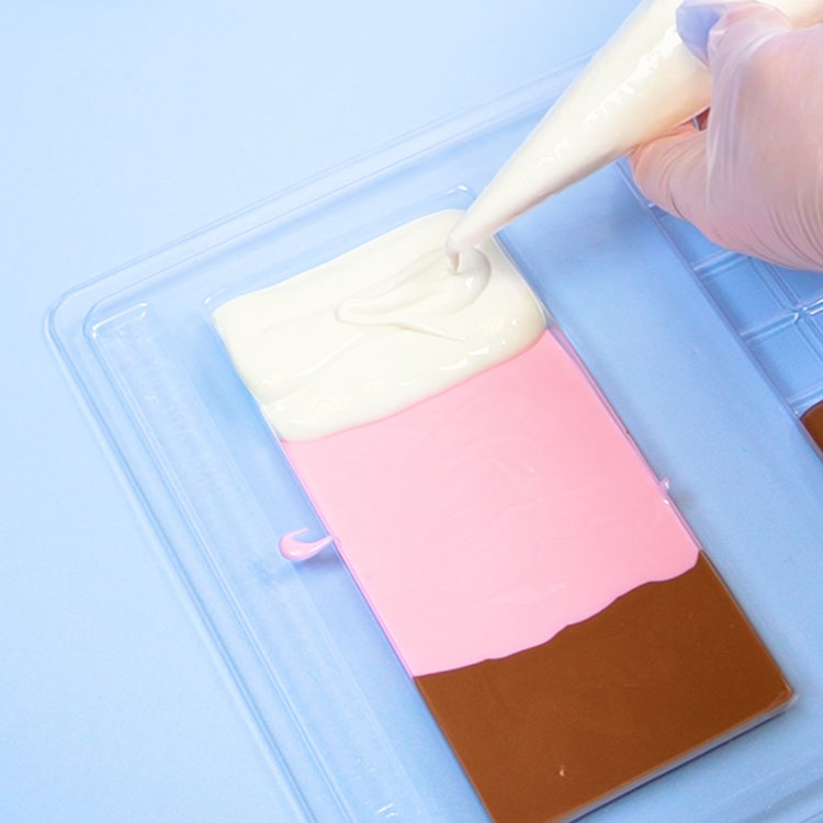 piping melted white chocolate into candy bar chocolate mold