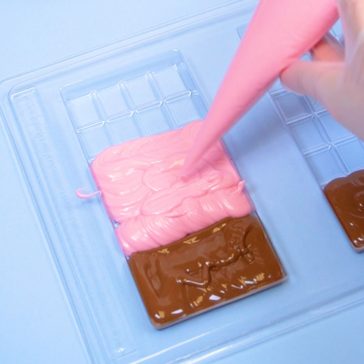 piping melted strawberry chocolate into candy bar chocolate mold
