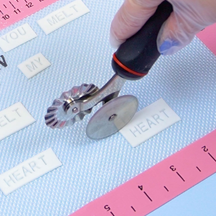 using a pastry wheel to trim off excess fondant