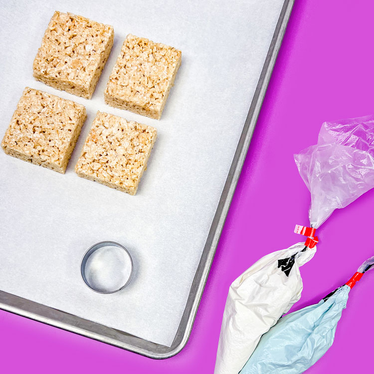 rice krispie treats on cookie sheet with round cookie cutter and tipless bags full of melted coating