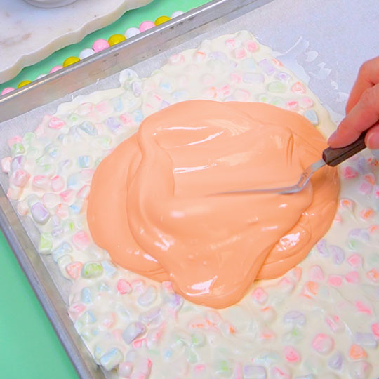 pouring orange chocolate onto cookie sheet