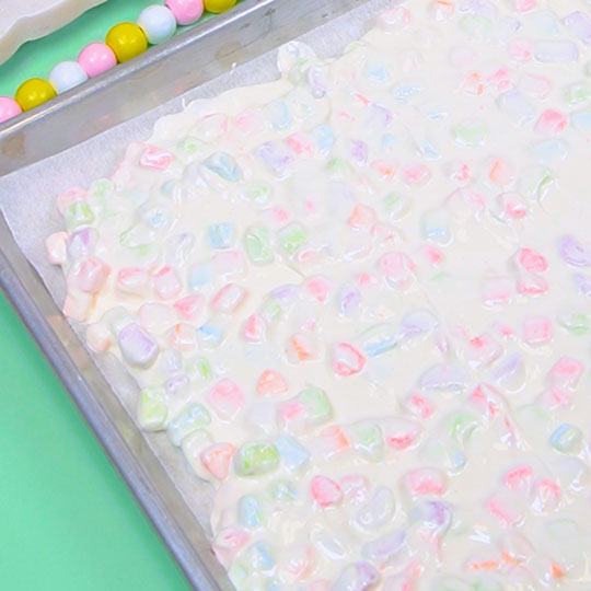 rainbow dehydrated marshmallows and white chocolate spread onto cookie sheet