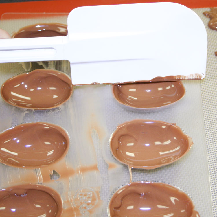 scraping access chocolate from easter egg chocolate mold.