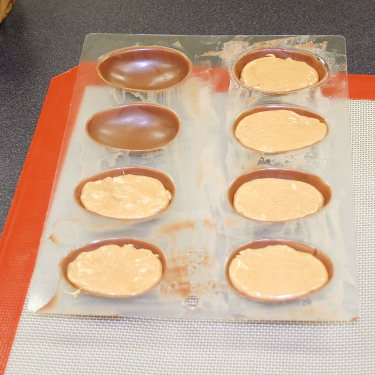 filling up chocolate egg shells with peanut butter candy center