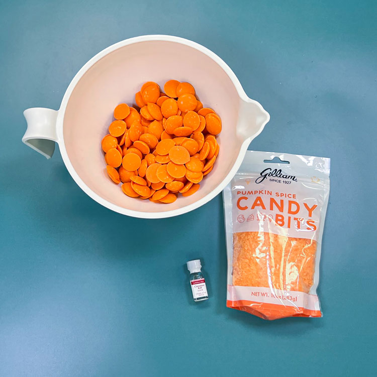 bowl of orange candy melts with pumpkin spice candy crunch and cinnamon bun flavoring.