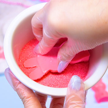 covering chocolate bunnies in pink sanding sugar