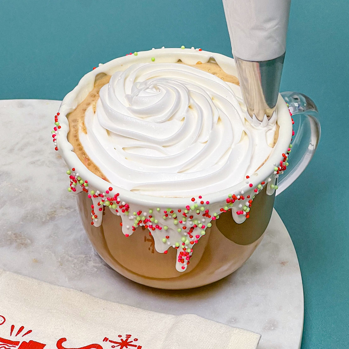 adding whipped cream to homemade sugar cookie latte