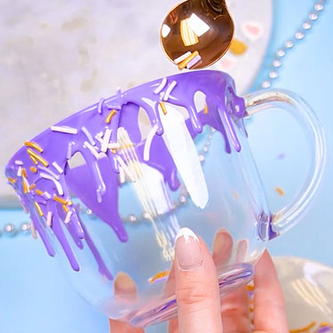 adding sprinkles to chocolate drip on mug