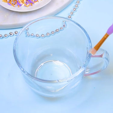 using a brush to add piping gel to rim of mug