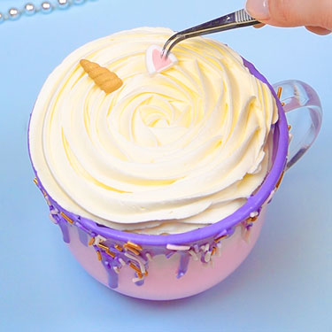 adding unicorn horn and ears on top of whipped cream using tweezers