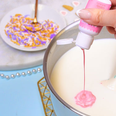 adding pink food coloring to hot chocolate mixture