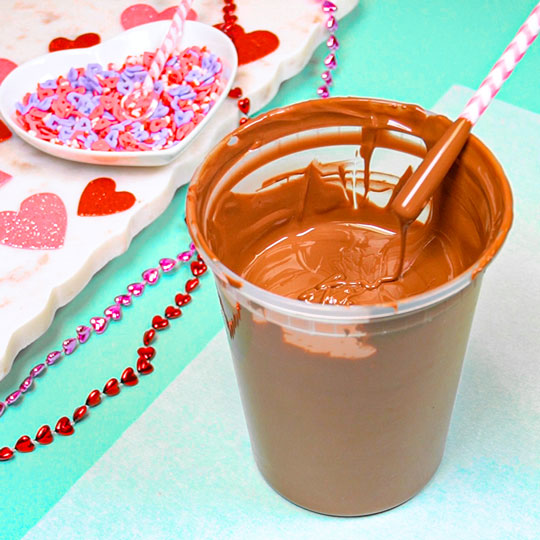 dipping straw into melted milk chocolate