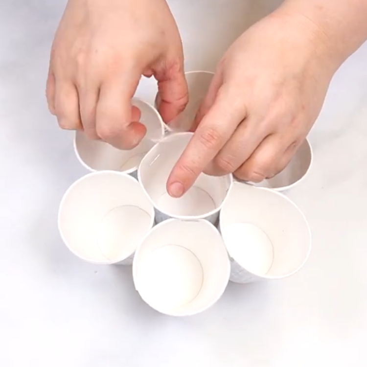 taping over the staples in the paper cups for a cupcake bouquet