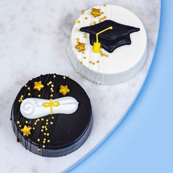 two chocolate dipped oreos decorated with graduation toppers
